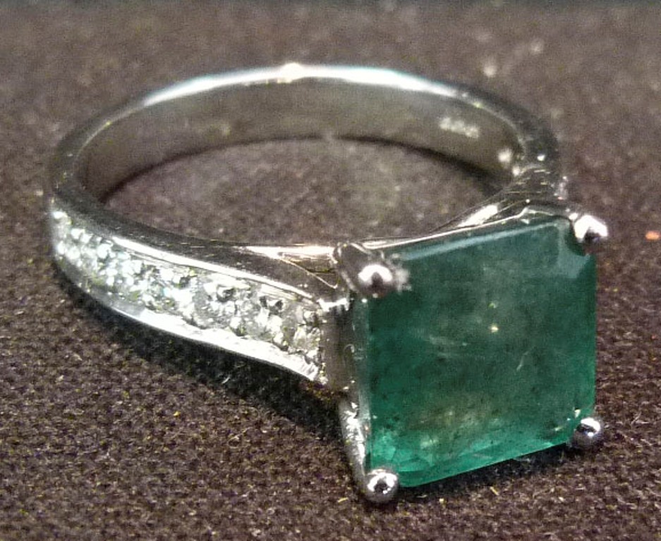 An 18ct. White Gold Emerald and Diamond Ring, set with a square emerald flanked by diamonds within a