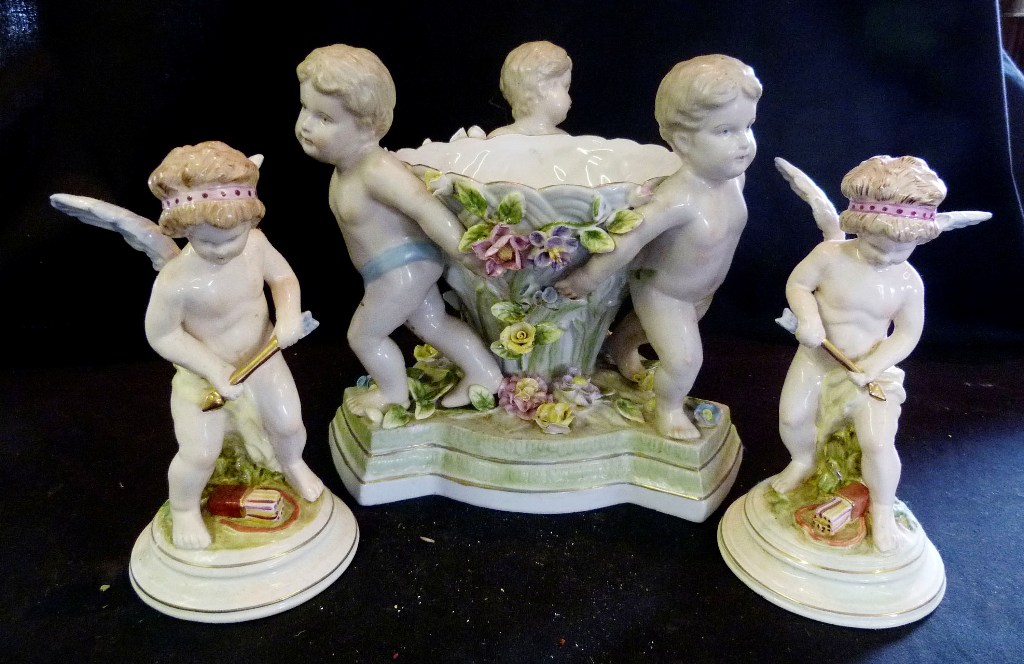 A Continental Porcelain Comport, supported by three putti together with a similar pair of models