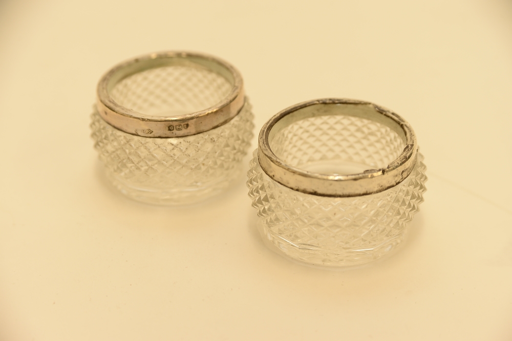 A pair of glass table salts with Hallmarked silver rims