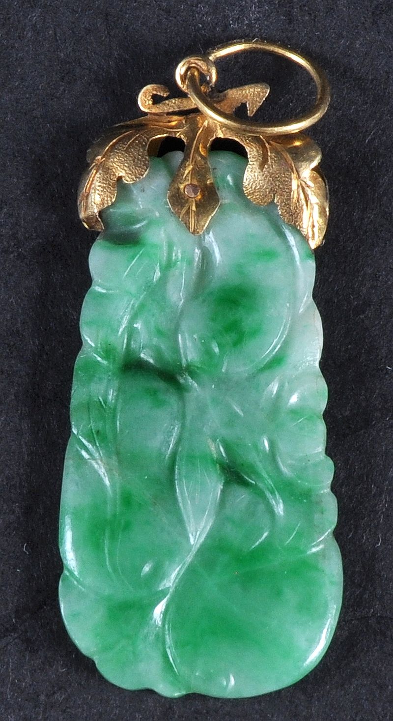 AN EARLY 20TH CHINESE YELLOW GOLD AND GREEN JADEITE PENDANT carved with a floral amulet, the jadeite