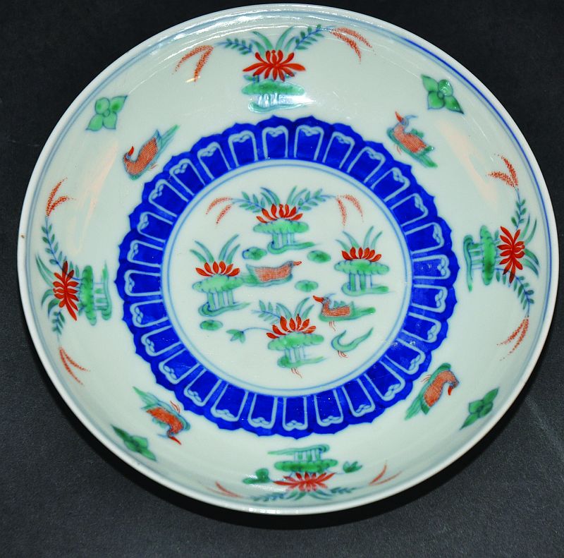 A CHINESE DOUCAI PORCELAIN SAUCER DISH, painted to its interior with ducks swimming amidst lotus,