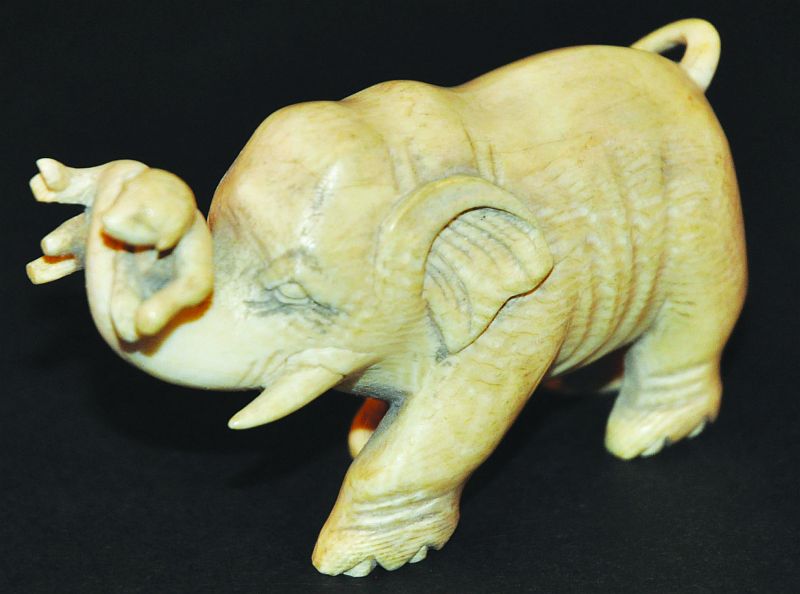 A JAPANESE CARVED IVORY OKIMONO OF AN ELEPHANT, circa 1900, bearing aloft a puppy in its trunk, 3.