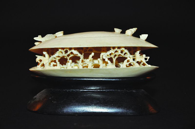 A JAPANESE IVORY OKIMONO OF THE CLAMS DREAM, together with a wood stand, the open interior of the