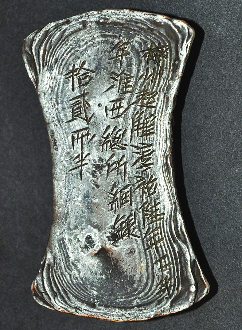 A CHINESE SILVER-METAL INGOT, weighing 439gm., the top surface incised with calligraphy, 3.5in long.