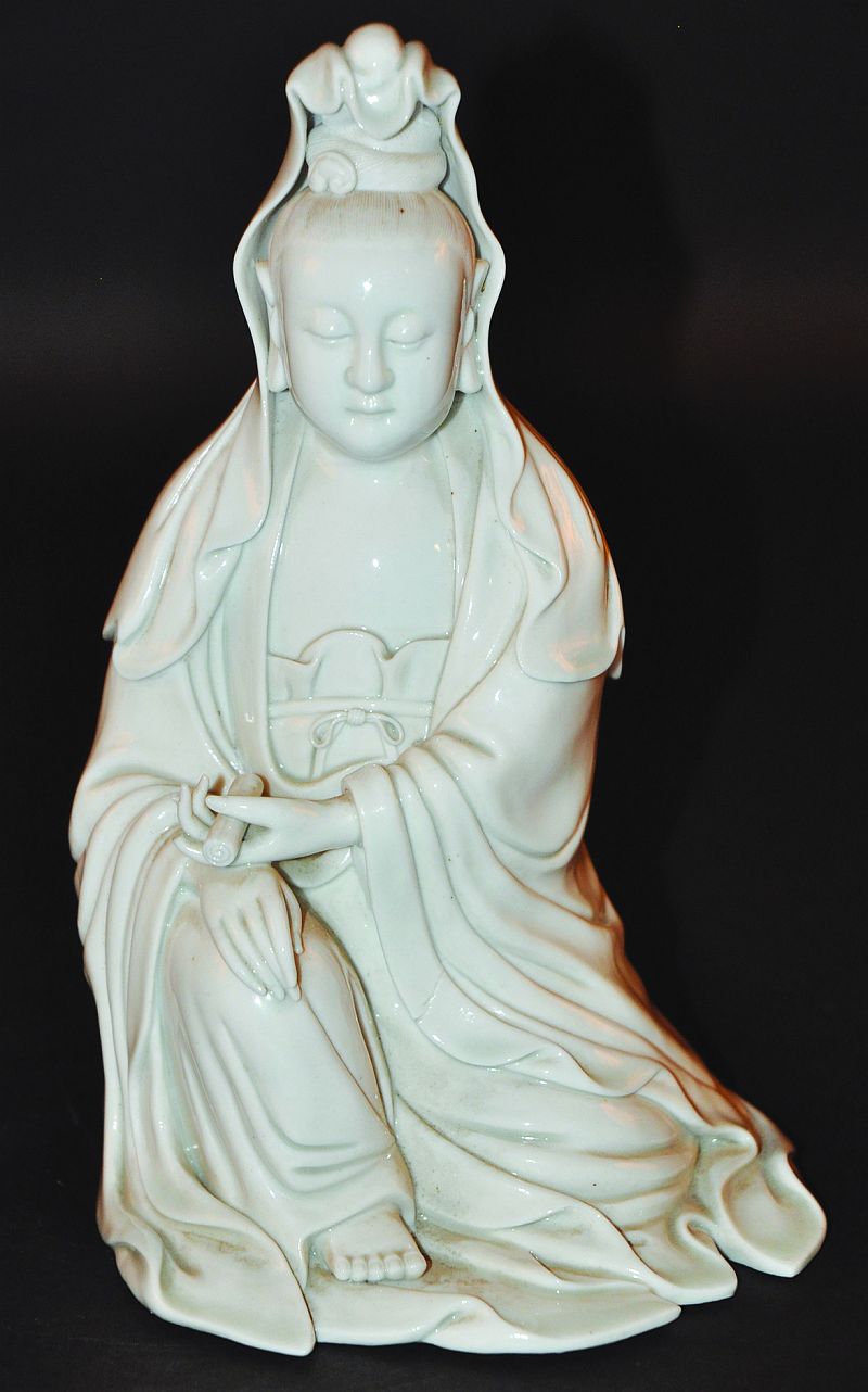 A CHINESE BLANC-DE-CHINE FIGURE OF GUANYIN, the goddess seated in flowing robes and holding a scroll