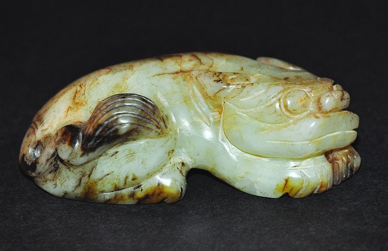 A 19TH/20TH CENTURY CHINESE CARVED JADE MODEL OF A BUDDHISTIC LION, rendered in archaic style, the