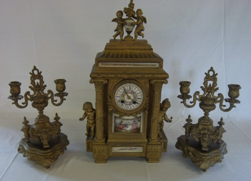 A French gilt brass japy freres 8 day clock garniture surmounted with cherubs holding a porcelain