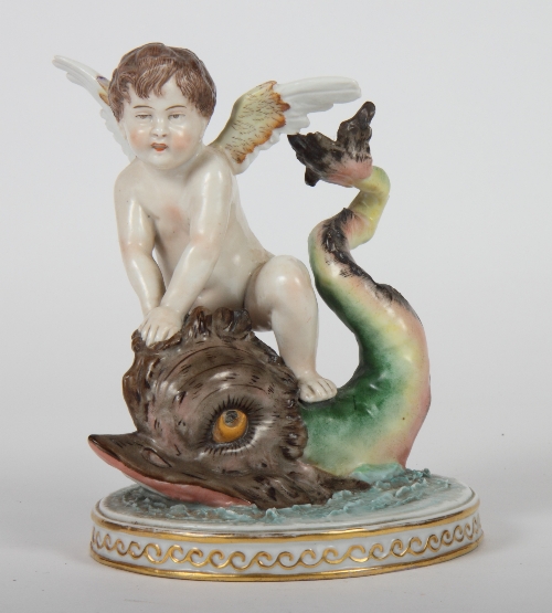 A 19th Century Naples porcelain figure of a boy on a dolphin, on oval gilt decorated base, 7" high