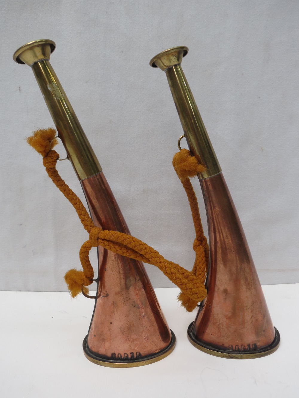 A pair of copper and brass curved hunting horns by North of Norfolk. 24cm.