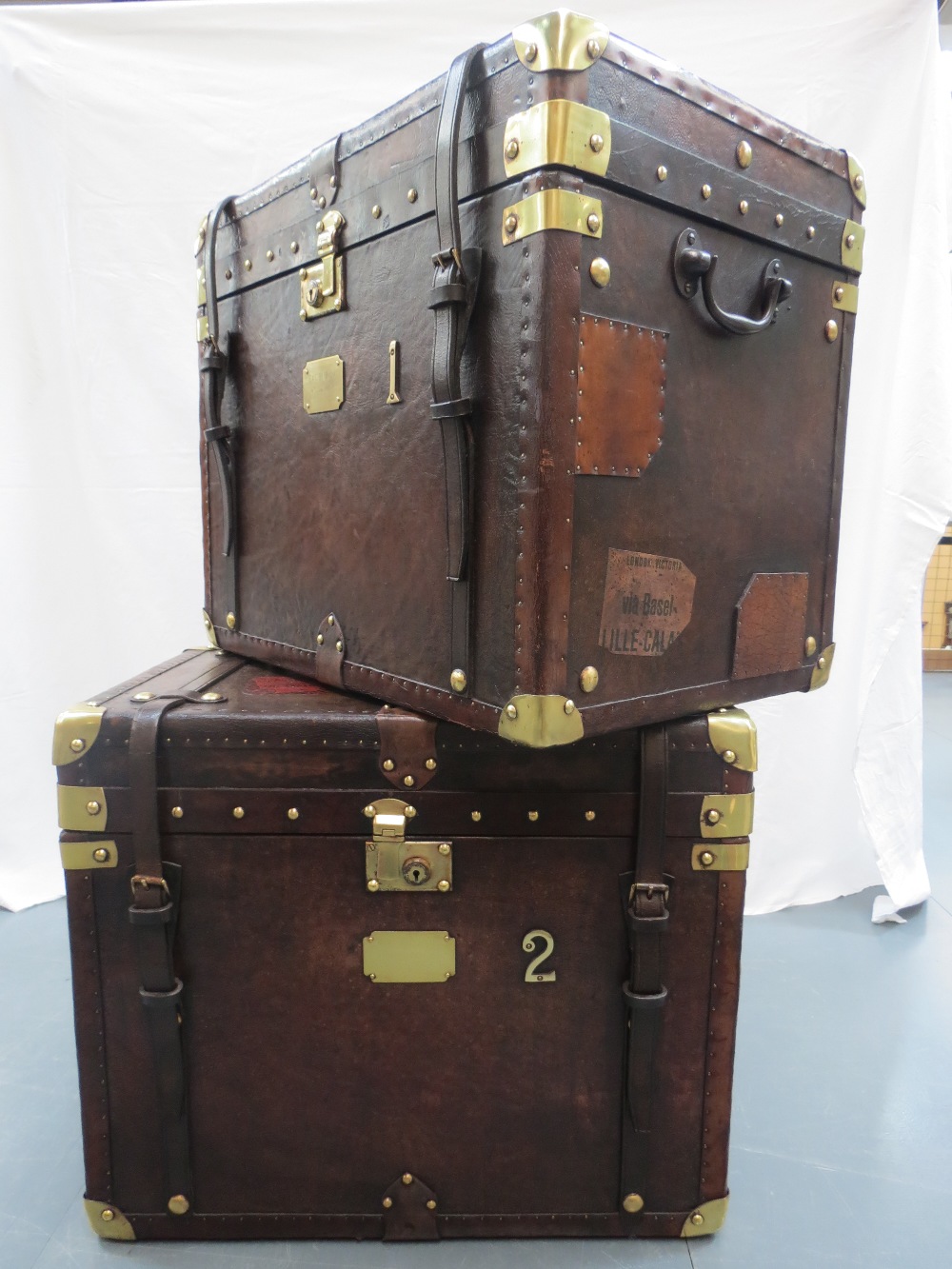 A pair of very handsome 'Army & Navy' leather trunks, brass corners and fittings, leather strap