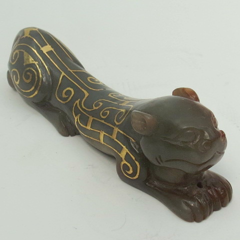 A Chinese dark green jade brush rest in animal form and having gold wire inlaid in swirling