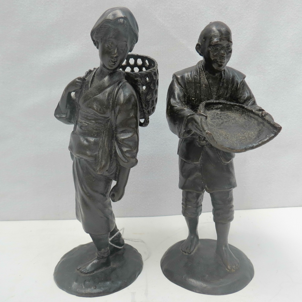 A pair of 19thC Oriental bronze figurines, man with wicker rice shaker, woman with wicker carry