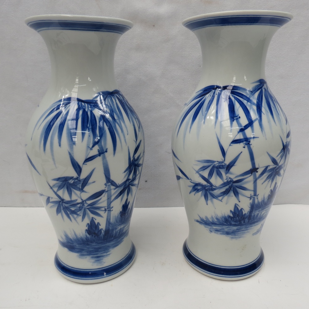 A pair of 20thC oriental blue and white vases with bamboo decoration, 27cm.