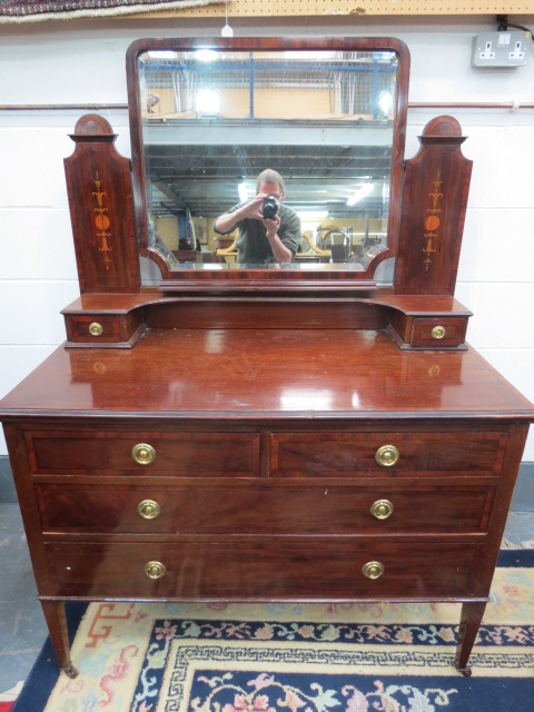 A smart and impressive dressing chest bevel edged mirror between twin supports inlaid with