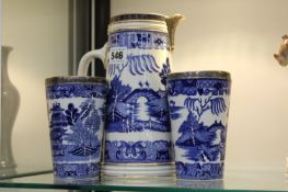 A WHITE METAL MOUNTED WILLOW PATTERN PITCHER AND TWO MATCHING BEAKERS
