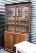 A GEORGIAN FLAME MAHOGANY GLAZED BOOKCASE ON CABINET