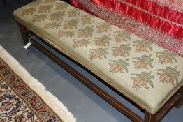 AN ARTS AND CRAFTS NEEDLEPOINT UPHOLSTERED LONG STOOL