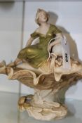 A ROYAL DUX ART NOUVEAU FIGURAL CENTREPIECE OF A WOMAN WITH A VASE SUPPORTED BY A SHELL AND LEAF