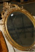 AN OVAL GILT FRAMED WALL MIRROR