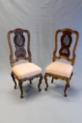 A pair of Continental carved high back chairs in Rococo style, each with elaborate pierced splats,