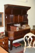 An Arts and Crafts oak dresser, the forward arch topped rack with cupboard and shelves over four