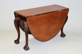 A carved mahogany drop leaf dining table in Chippendale style, the moulded edge shaped top on bold