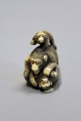 A Japanese Meiji carved ivory netsuke depicting a monkey with two baby monkeys, signed to the