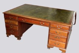 An early 20th Century mahogany twin pedestal partner’s desk, the tooled leather writing surface