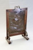 An Arts and Crafts copper and oak framed firescreen possibly Newlyn, the beaten copper panel