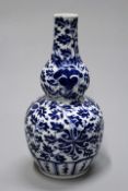 A Chinese blue and white gourd form vase with scrolling foliage decoration over all, 23cm high.