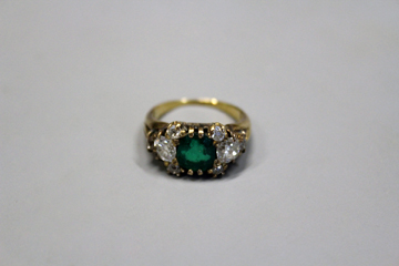 A diamond and emerald dress ring, unmarked yellow metal mount.