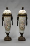 A pair of late 19th/early 20th Century gilt brass mounted porcelain lidded urns, each with hand
