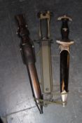 A German Mauser bayonet contained in its steel scabbard, an American M7 bayonet with scabbard and