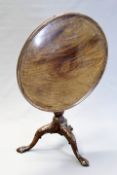 A George III and later carved mahogany tilt top table, the dished circular top with revolving bird