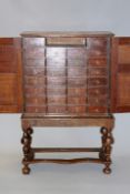 An early 18th Century oak cabinet on stand the twin panel doors enclosing an array of small