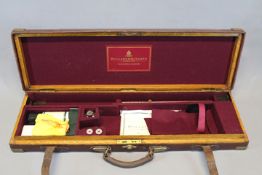 An Holland & Holland leather covered oak sporting gun case, the burgundy baize lined interior for