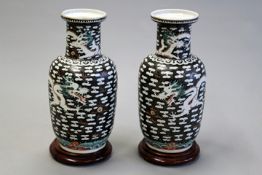 A pair of Chinese Rouleau vases decorated with writhing dragons amidst clouds, 36cm high. (2)