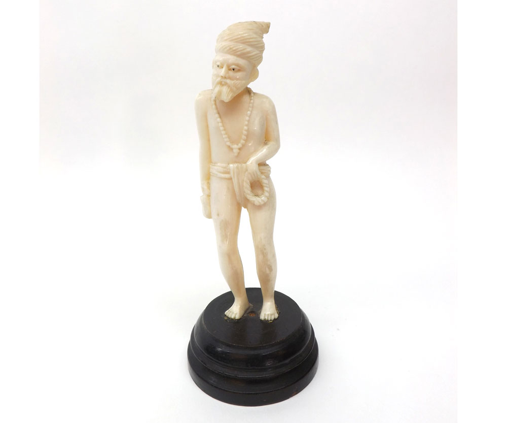 A carved Ivory Figure of a Pearl Diver clutching a rope ring in one hand and with a pouch in the