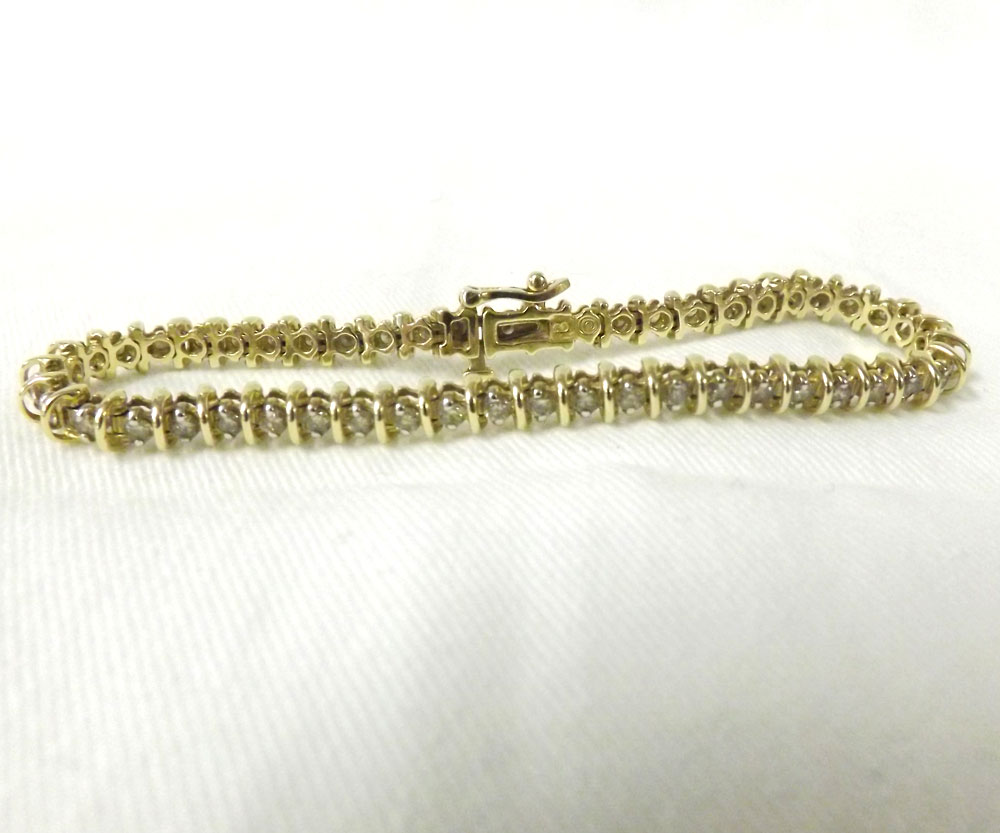 A mid grade yellow metal Line (or Tennis) Bracelet set with approximately 50 small brilliant cut