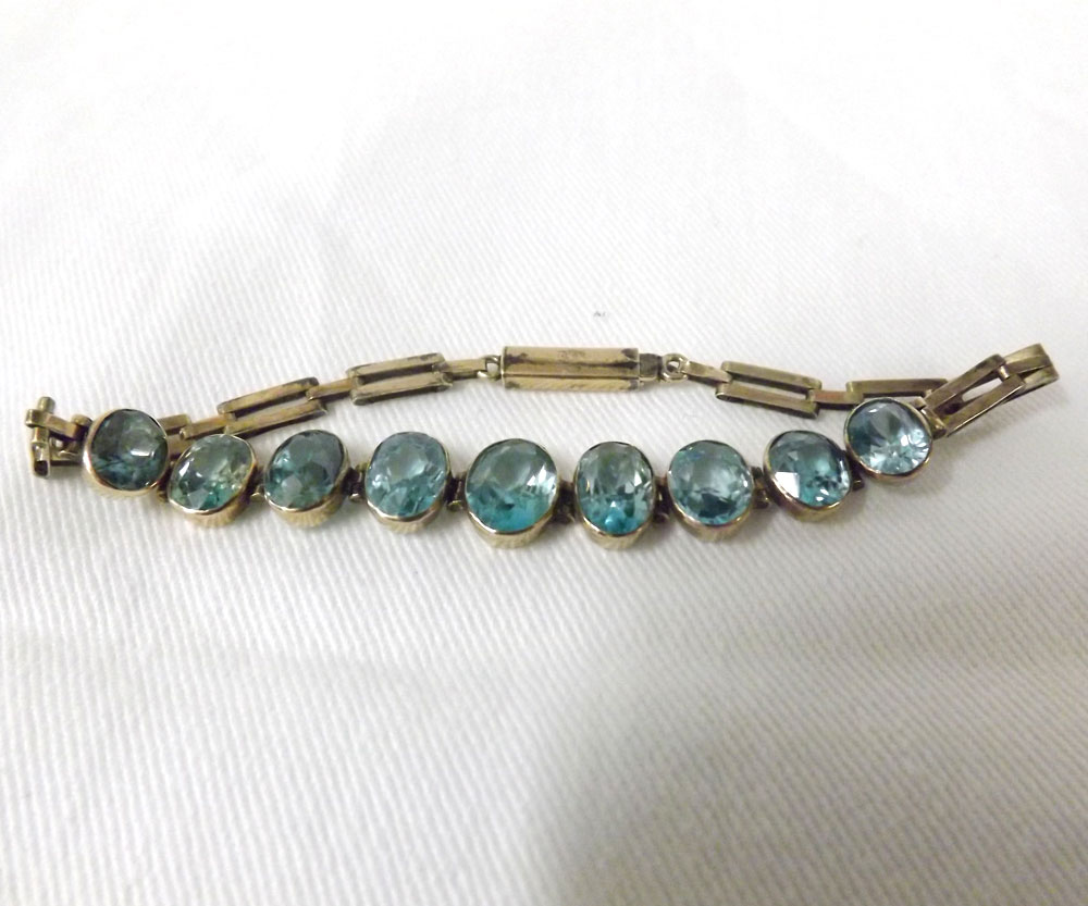 An early 20th Century precious metal link Bracelet featuring nine graduated oval cut Zircons to the