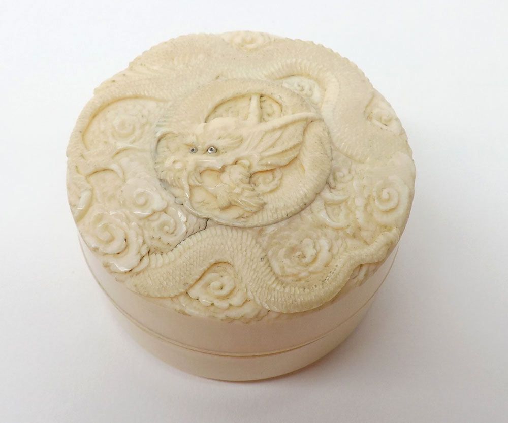 A circular carved Ivory Box with pull-off cover, the lid carved with a coiled dragon, 2 ½" diameter