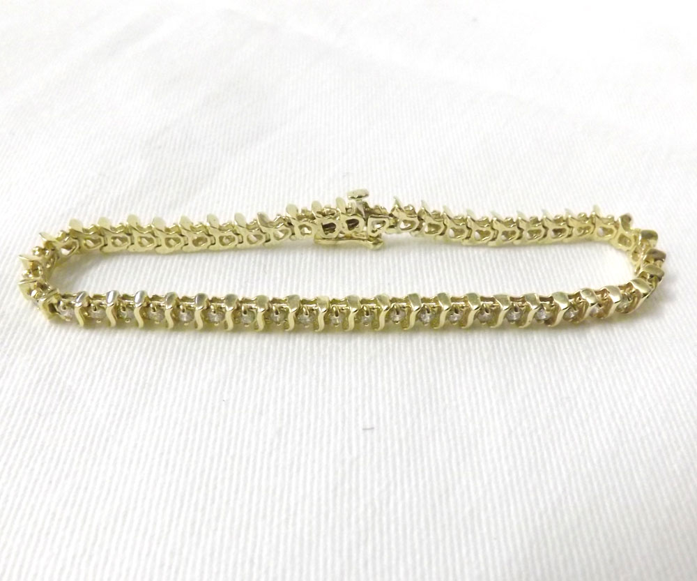 A mid-grade yellow metal Tennis (or Line) Bracelet, set with forty-nine small Brilliant Cut