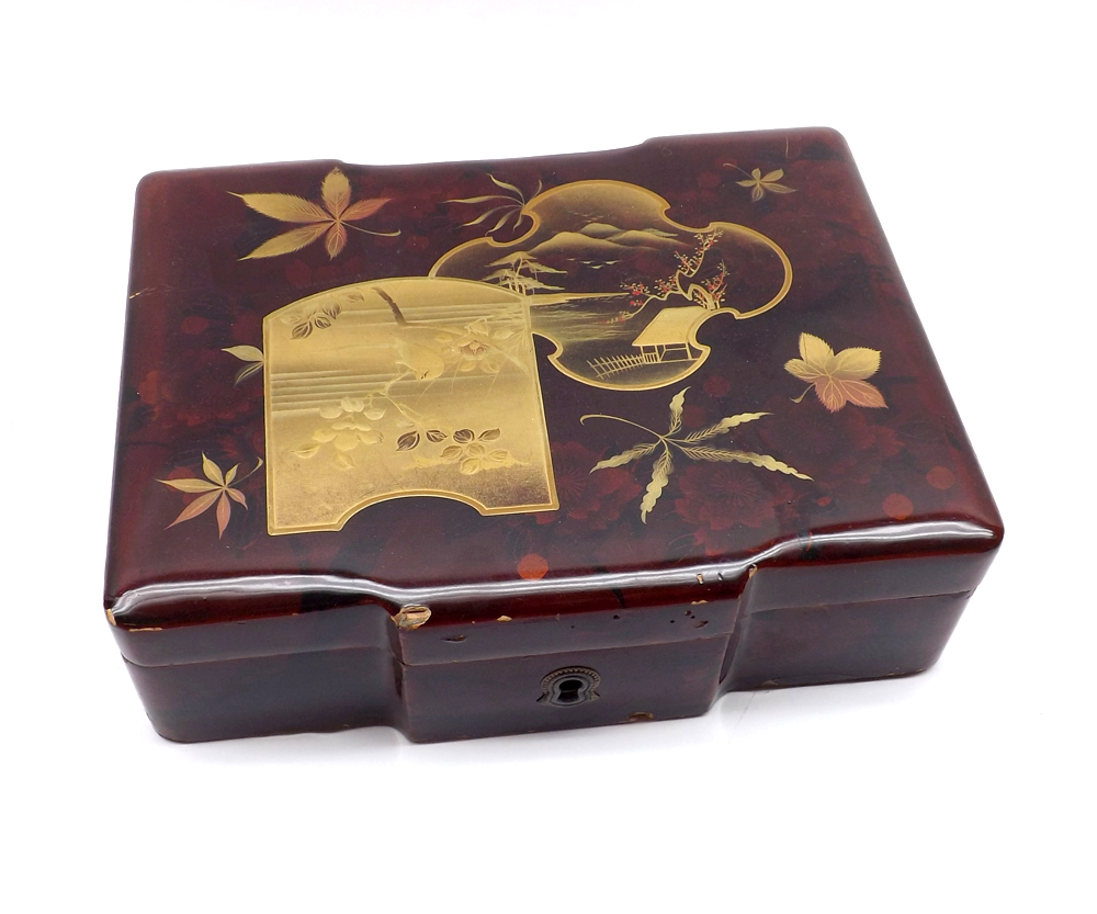 An Oriental Lacquered Box containing a small collection of various base metal mounts in the forms