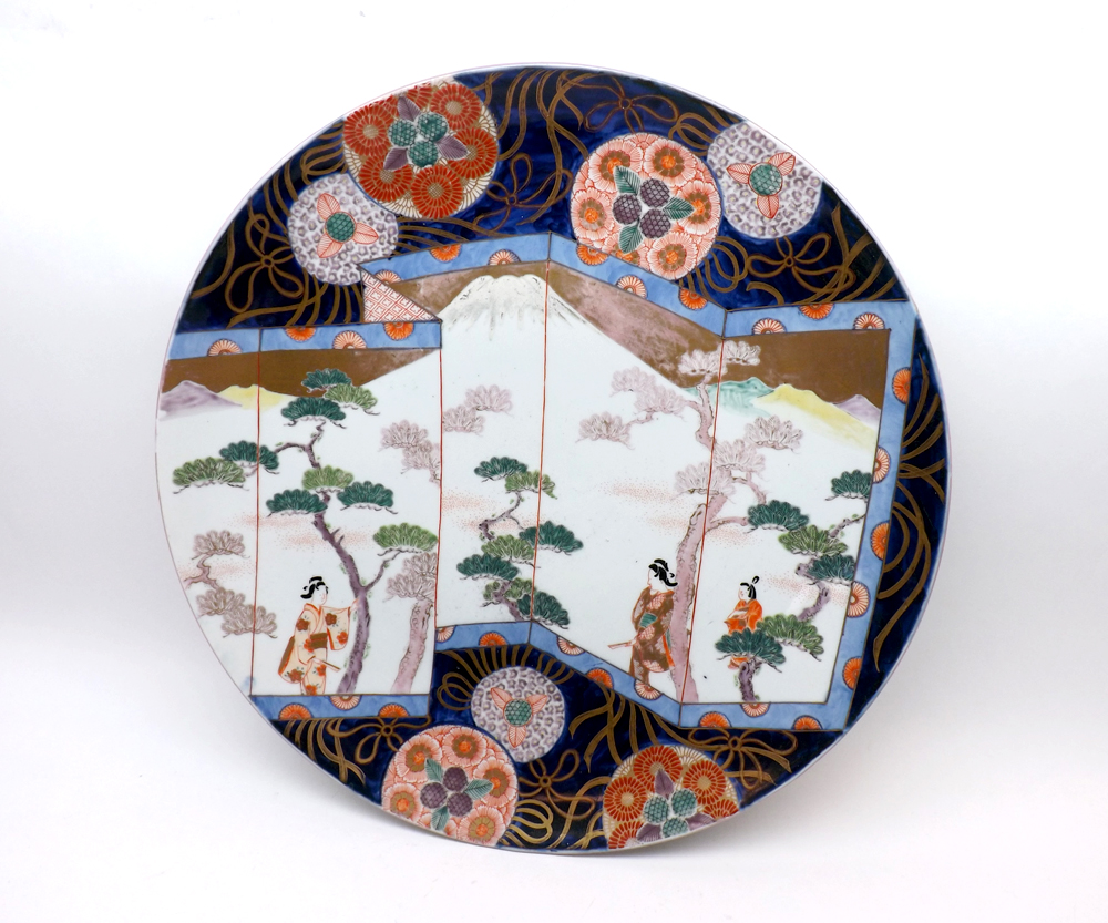 A large Imari style Charger, the centre unusually decorated with a folding screen and figures with