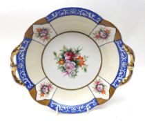 A Noritake Dish of two-handled shaped circular form, the centre decorated in colours with a spray of