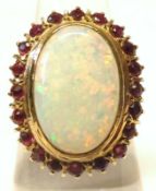 A large Centre Opal (16mm x 11mm) and small Ruby Surround Cluster Ring, pierced oval setting,