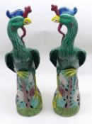 A pair of 20th Century Oriental Majolica type Models of perched peacocks, decorated in green,