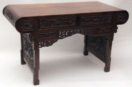 An Oriental Hardwood Large Side Table, plain top with curved ends, the carved front decorated with