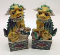 A pair of 20th Century Models of temple dogs, decorated in green and lemon, 6” high