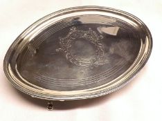 A George III Oval Teapot Stand, with central engraving and vacant cartouche, raised on four small